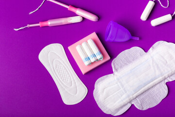 Menstrual cup, pad and tampons to create protection during menstruation. Feminine hygiene concept. Women's health. Menstrual cup, pad, tampons on violet background. Hygiene products for women. © Julia