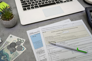 Obraz premium Polish tax forms PIT-38, PIT-36 PIT-37 polish tax form, pln zloty money pen laptop on desk