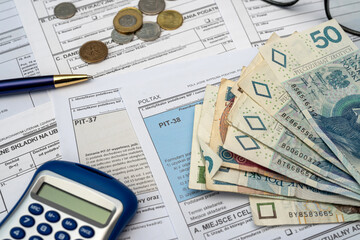 Polish declaration PIT-36L, PIT-37 and PIT-38 tax forms with pln zloty money pen calculator glasses on desk