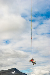 Motorcycle suspended in the air over rugged Swedish landscape with dramatic clouds