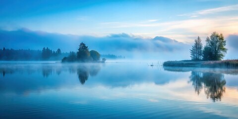Fototapeta premium A serene lake mirroring the soft hues of a misty dawn with distant trees and a gentle breeze