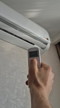 Man turns on air conditioner with remote control, close-up