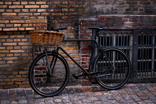 A city bike with shopping basket leans against an old house wall.
