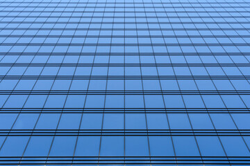 Fragment of a modern high-rise with glass walls. Beautiful blue background