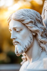 A sculpted statue of Jesus Christ stands bathed in sunlight. Soft focus and a warm glow emphasize his peaceful face. Trees create a blurred background in the outdoor setting