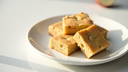 Golden-brown baked squares arranged on a pristine white plate, bathed in soft sunlight, a delightful treat for the senses.