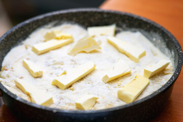 homemade raw apple pie in a baking dish, topped with generous chunks of butter, ready for baking. The pie features a flaky crust and fresh apple filling, perfect for dessert