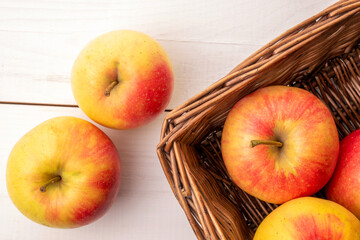 Several juicy apples with a basket on a wooden table, close-up, top view.