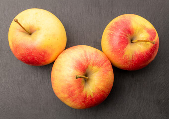 Three juicy apples on a slate stone, macro, top view.