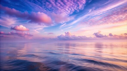 Obraz premium A pastel sky with cotton candy clouds reflects in the rippling surface of the ocean, creating a serene and ethereal scene.