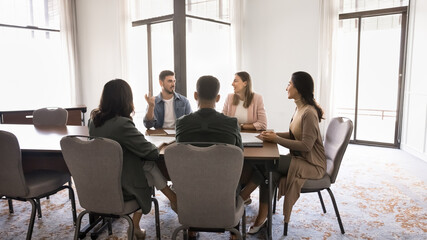 Group of five professionals sitting around conference table solve work-related matters, exchanging...