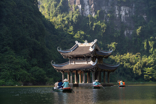Tourists rowing boats visiting temple on Trang An Scenic Landscape Complex, Ninh Binh Province, Vietnam