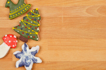 A top-down shot of Christmas-themed cookies, including a Christmas tree, rocking horse, star, and mushroom, placed on a wooden table with ample copy space