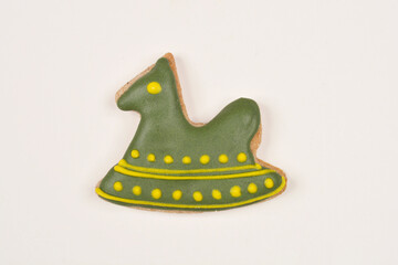 A top-down shot of a rocking horse-shaped cookie with green and yellow icing on a light background
