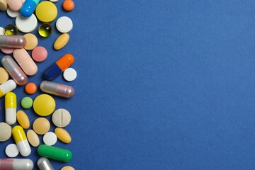 Various pills on blue background, top view
