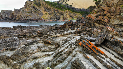 Obraz premium A rocky bay in Australia covered in orange lichen, seen from above