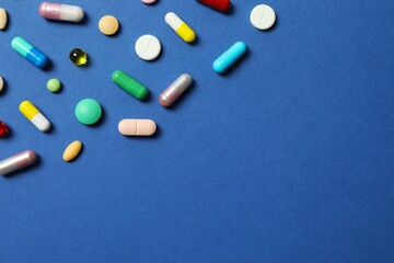 Various pills on blue background, top view