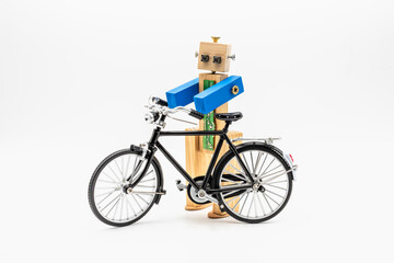 Pequeño robot hecho de madera y tornillos con una bicicleta clásica en miniatura, aislado en...