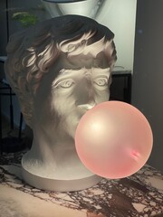 Statue of a mans face blowing a bubble which is a lamp