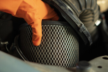 Auto mechanic checking, cleaning and replacing car air filter. Concept of car care service maintenance.