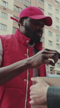 Face courier African American gives a parce to a woman after signing on delivery device cardboard technology box order post postal service device sunny beard covered load logistic slow motion