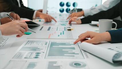 A collaborative business meeting featuring diverse hands engaged in the analysis of data charts and graphs on a table. Professionals collaborate on strategies and insights. SACTR