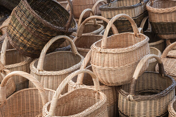 a lot of various wicker baskets with handles displayed at a market