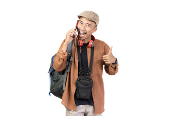 Excited young Indonesian man giving thumbs up to camera, travel concept, isolated on white background.