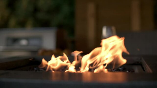 Cozy Outdoor Fire Pit with Flames and Wine Glass warm outdoor fire pit with dancing flames, creating cozy atmosphere wine glass is seen in blurred background, suggesting relaxation evening setting