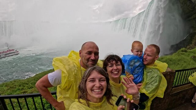 Happy Tourists Taking Selfie at Niagara Falls joyful group of tourists rain ponchos takes selfie near Niagara Falls, with mist tour boat visible in background fun travel moment this iconic destination