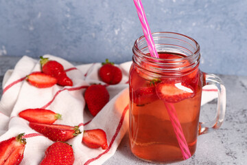 Mason jar of tasty strawberry juice on grey table