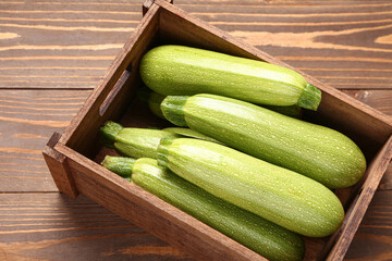 Box with fresh green zucchini on wooden background