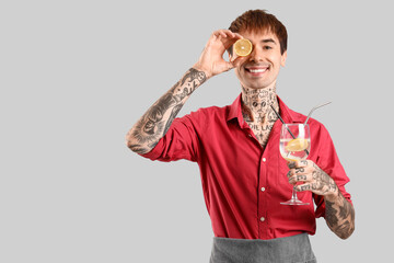 Funny male bartender with lime and glass of cocktail on white background