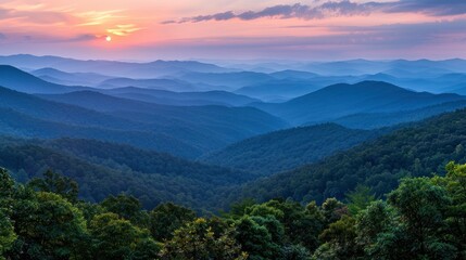 Fototapeta premium Serene sunset over rolling mountains, showcasing layers of blue hills and lush greenery below