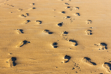 Tracks from different people in various shoes on yellow sand. Pattern.