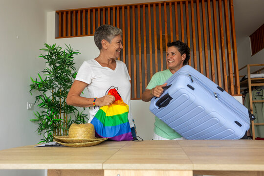 Two lesbians pack luggage, excited for summer holidays