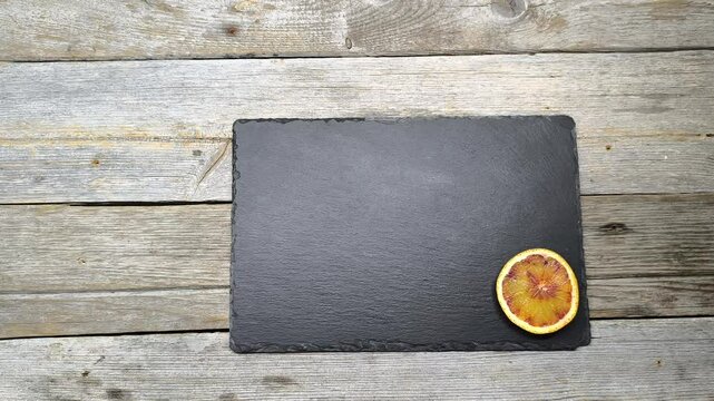 a slice of orange lies on a granite board