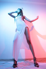 Elegant Young Woman in White Slit Dress Posing Against Pink Background