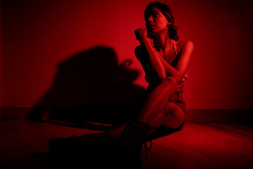 Stylish Young Woman in Denim Skirt and Crop Top Shot Under Red Lighting Against Wall