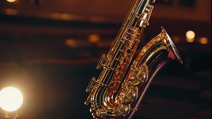 Shiny golden saxophone in warm dim light against blurred background of jazz club with glowing lamps. Concept of live music and nightlife atmosphere