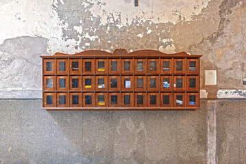 A bank of wall-mounted wooden letterboxes on the facade of an apartment building in the old town of Naples. The mailboxes are in Renaissance style. 