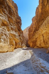 Stone canyon path. Sand ground between tall rock walls. Sunny day with blue sky. Canyon nature scene.