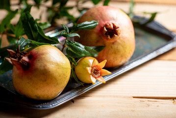 Pomegranates, beautiful freshly picked pomegranates on a wonderful tray on a rustic surface,...