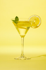 Glass of lemonade with mint against yellow background.