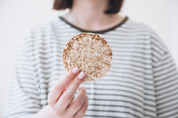 Close-up, rice cake in the hands of a woman, diet crispy round rice waffle.