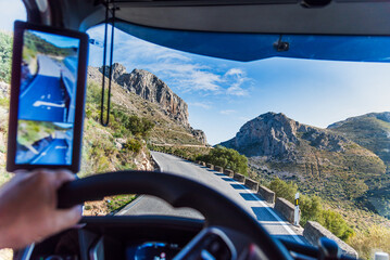 View from the driver's seat of a truck on a high mountain road, narrow, dangerous, and single-lane.