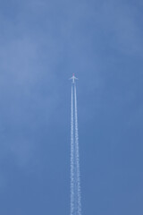 A jet is flying through the sky leaving a trail of smoke behind it