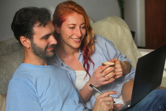 man and woman working at home on laptop computer talking and smiling