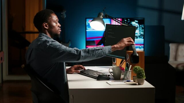 Young programmer engineer writing binary code data on terminal window, doing freelance work at home setup. Software developer working on troubleshooting with programming language. Camera B.