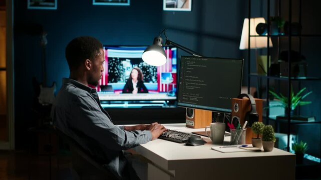 African american expert at desk using pc for programming and data analysis. Young networking expert working from his home setup, manages information technology and data center. Camera B.
